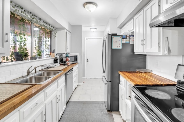 kitchen featuring ventilation hood, butcher block countertops, stainless steel appliances, and white cabinetry