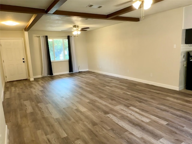 unfurnished living room with a large fireplace, ceiling fan, beamed ceiling, and wood-type flooring