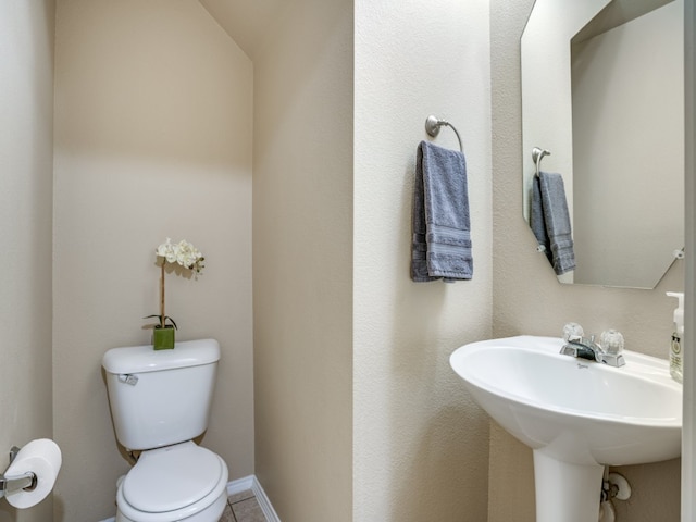 bathroom featuring lofted ceiling, tile patterned flooring, toilet, and sink