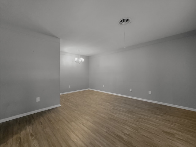 empty room featuring wood-type flooring and a chandelier