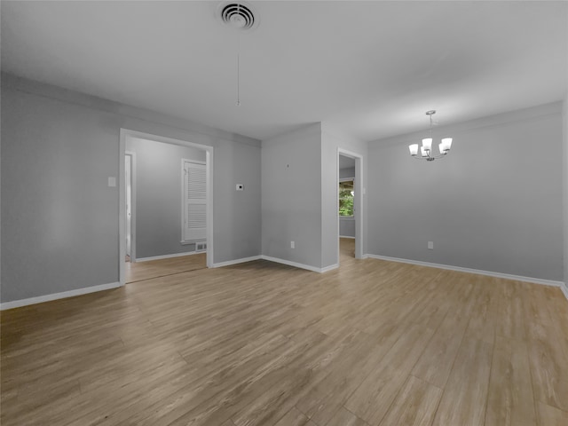 spare room featuring crown molding, a notable chandelier, and light hardwood / wood-style flooring