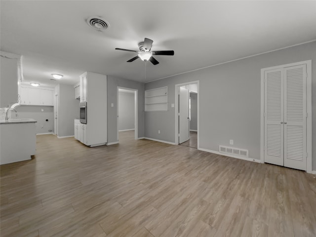 unfurnished living room featuring ceiling fan, light hardwood / wood-style floors, and sink