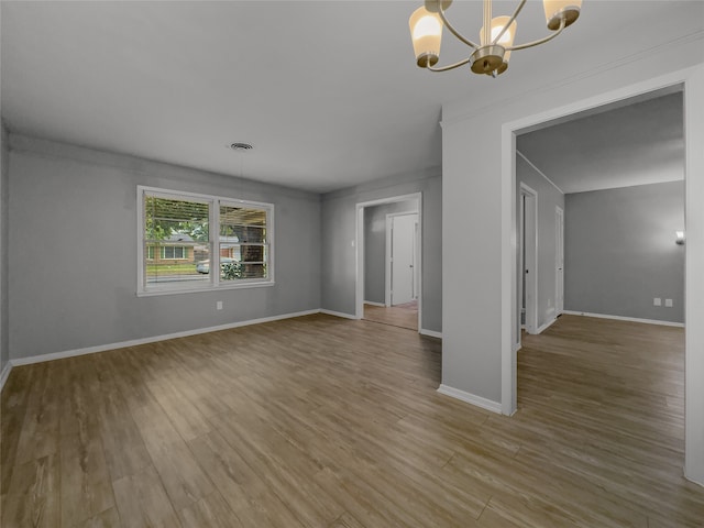 empty room with hardwood / wood-style flooring and a chandelier