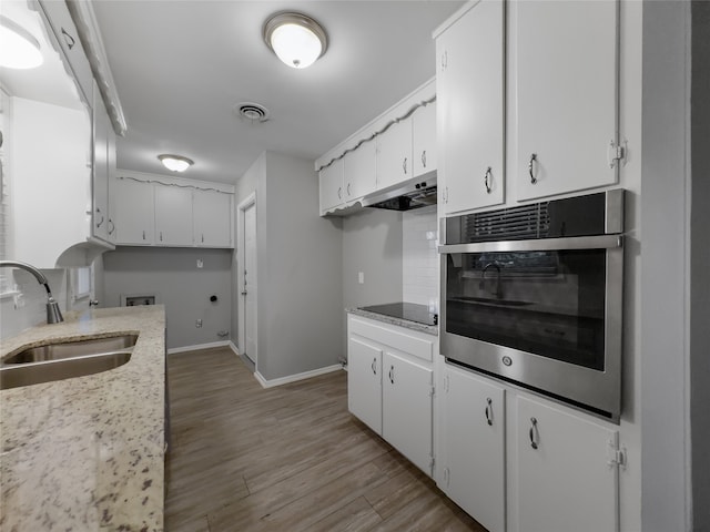 kitchen with oven, light hardwood / wood-style floors, sink, decorative backsplash, and white cabinetry