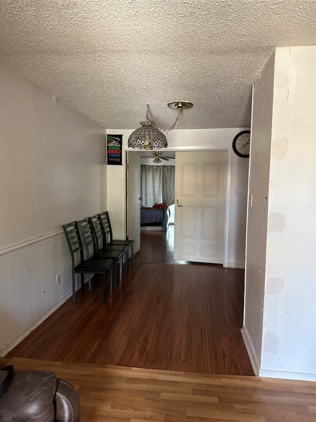 unfurnished dining area featuring a textured ceiling and dark wood-type flooring