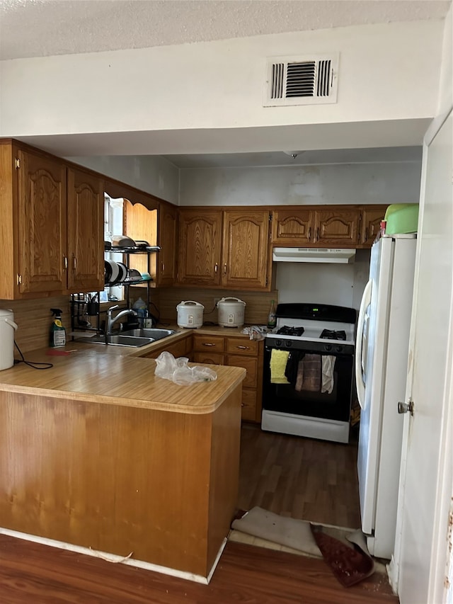 kitchen featuring kitchen peninsula, sink, white appliances, and dark hardwood / wood-style flooring