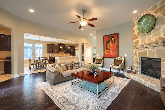 living room featuring hardwood / wood-style floors, a stone fireplace, and ceiling fan