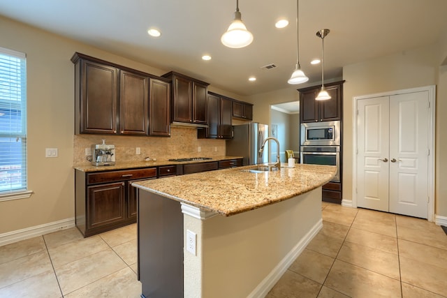 kitchen with an island with sink, light stone counters, dark brown cabinetry, and appliances with stainless steel finishes