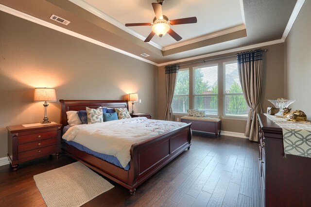 bedroom featuring crown molding, ceiling fan, a tray ceiling, and dark hardwood / wood-style flooring