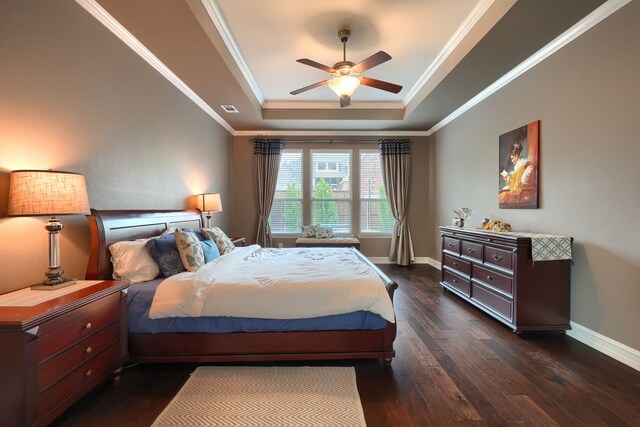 bedroom featuring ornamental molding, dark hardwood / wood-style flooring, a tray ceiling, and ceiling fan