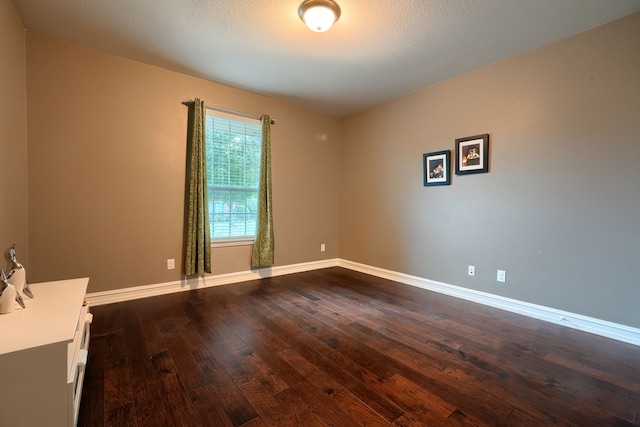 unfurnished room featuring dark hardwood / wood-style flooring and a textured ceiling