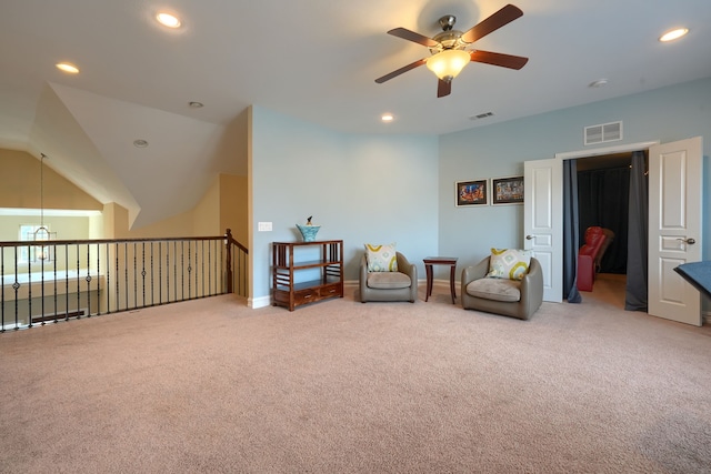 living area with lofted ceiling, ceiling fan, and light carpet