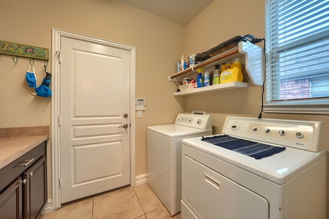 laundry room featuring washing machine and dryer, cabinets, and light tile patterned floors