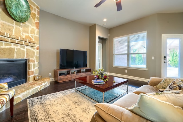 living room with dark wood-type flooring, ceiling fan, and a fireplace