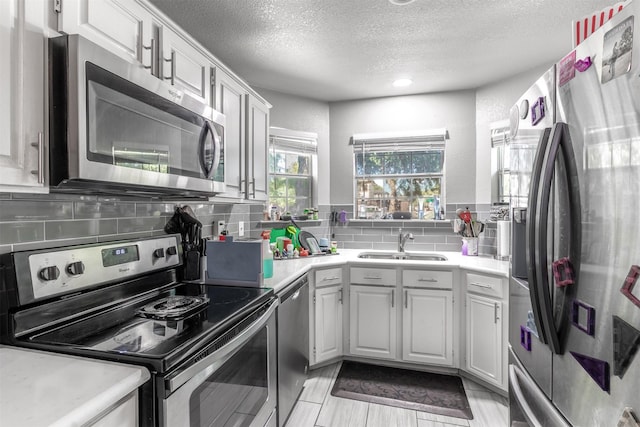 kitchen featuring decorative backsplash, appliances with stainless steel finishes, a textured ceiling, sink, and white cabinetry