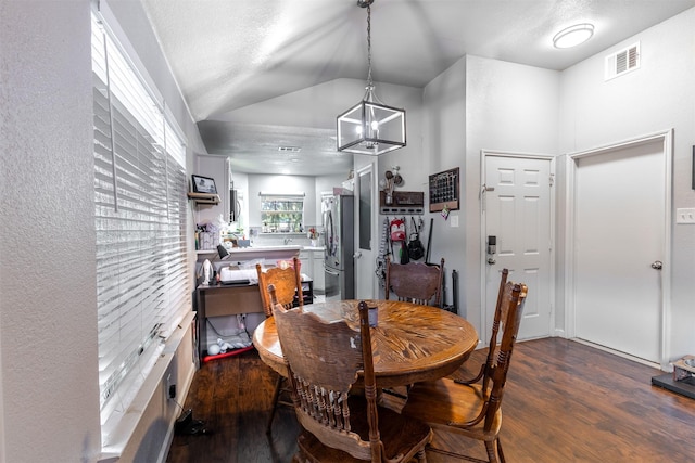 dining area featuring a textured ceiling, dark hardwood / wood-style floors, lofted ceiling, and an inviting chandelier