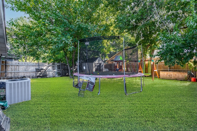 view of yard featuring a trampoline and central AC