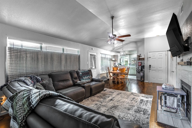 living room featuring ceiling fan, dark hardwood / wood-style flooring, lofted ceiling, and a textured ceiling