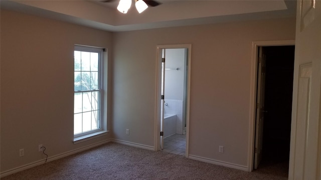 unfurnished bedroom featuring ensuite bath, multiple windows, light carpet, and a spacious closet