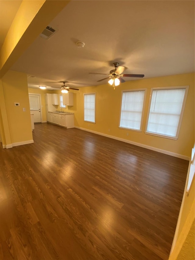 unfurnished living room with dark hardwood / wood-style flooring and ceiling fan