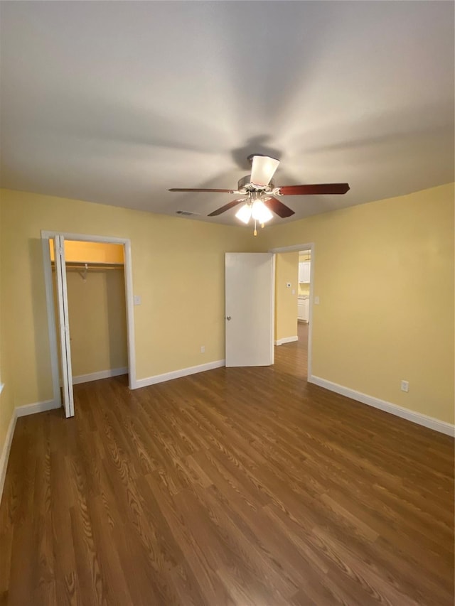 unfurnished bedroom with ceiling fan, dark hardwood / wood-style flooring, and a closet