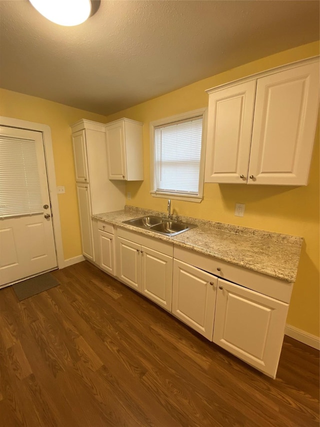 kitchen featuring dark wood-type flooring, sink, white cabinetry, a textured ceiling, and light stone countertops