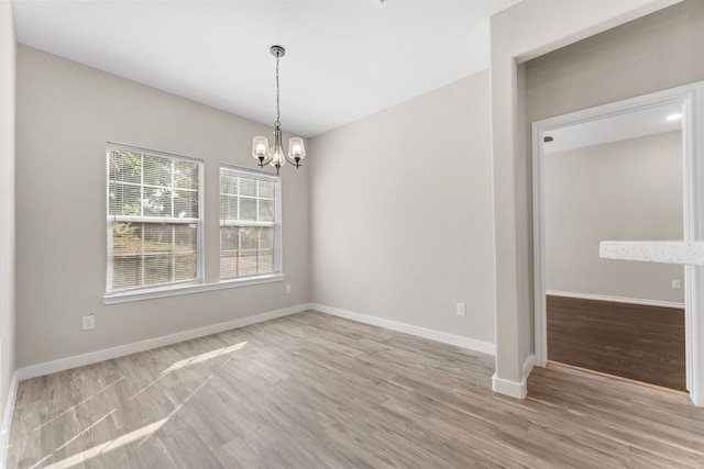 unfurnished room featuring a chandelier and light hardwood / wood-style floors