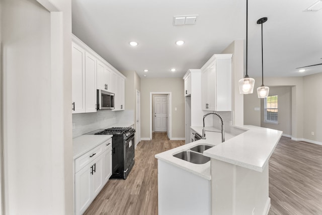 kitchen with sink, gas stove, decorative light fixtures, white cabinets, and backsplash