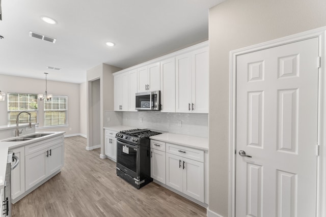 kitchen featuring sink, hanging light fixtures, stainless steel appliances, decorative backsplash, and white cabinets