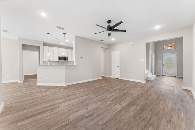 unfurnished living room with ceiling fan and light hardwood / wood-style flooring