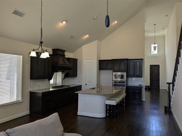 kitchen featuring stainless steel gas cooktop, light stone counters, tasteful backsplash, and sink