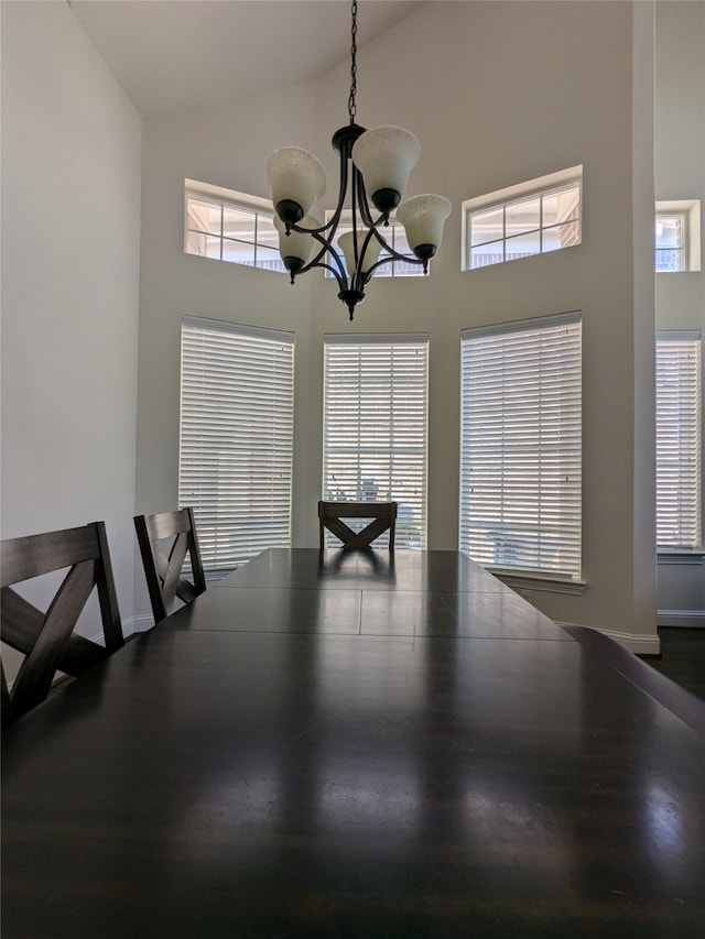 unfurnished dining area featuring high vaulted ceiling, hardwood / wood-style flooring, and an inviting chandelier