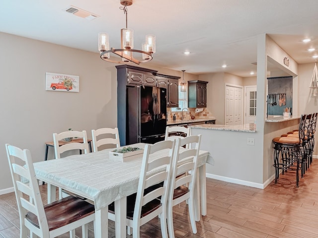 dining area featuring an inviting chandelier, light hardwood / wood-style flooring, and sink