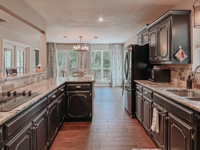 kitchen with backsplash, black appliances, sink, hanging light fixtures, and dark hardwood / wood-style flooring