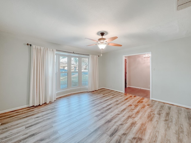 empty room with ceiling fan and light hardwood / wood-style flooring