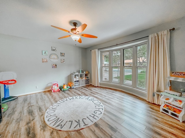 playroom with light hardwood / wood-style floors and ceiling fan