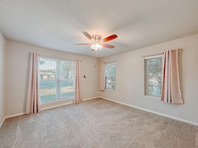 unfurnished room with a textured ceiling, ceiling fan, and light colored carpet