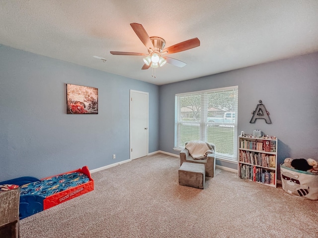 sitting room with ceiling fan, a textured ceiling, and carpet flooring