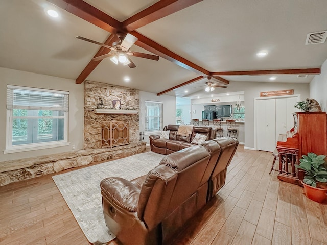 living room with a fireplace, light hardwood / wood-style flooring, ceiling fan, and vaulted ceiling with beams