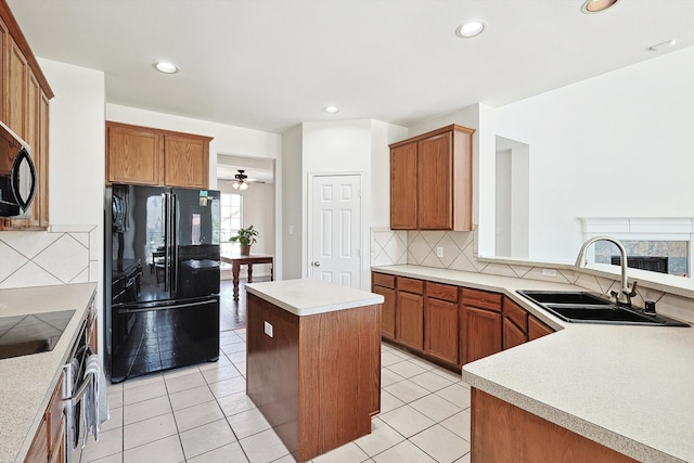 kitchen with light tile patterned floors, light countertops, decorative backsplash, a sink, and black appliances