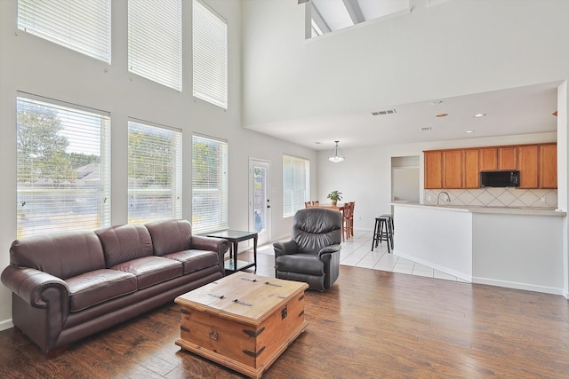 living area with recessed lighting, wood finished floors, visible vents, and baseboards