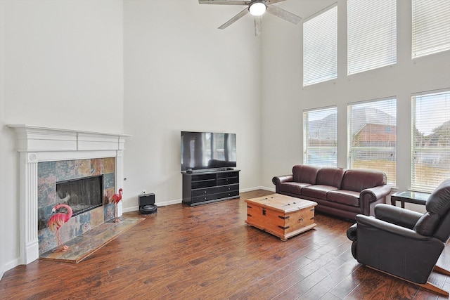 living room featuring a tile fireplace, plenty of natural light, baseboards, and wood finished floors