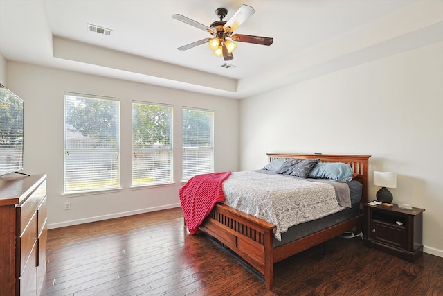 bedroom featuring hardwood / wood-style floors, a raised ceiling, visible vents, and baseboards