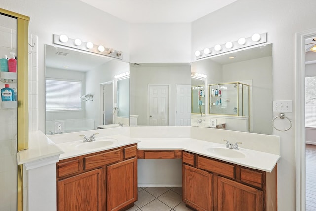 bathroom featuring a stall shower, double vanity, a sink, and tile patterned floors