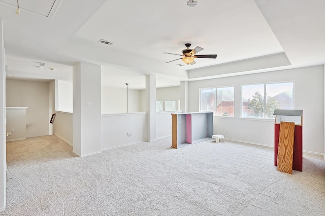 carpeted spare room featuring attic access, baseboards, visible vents, ceiling fan, and a tray ceiling