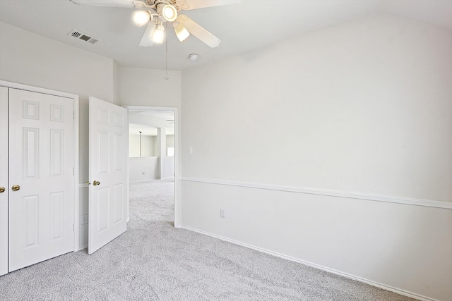 unfurnished bedroom featuring visible vents, lofted ceiling, ceiling fan, carpet, and a closet