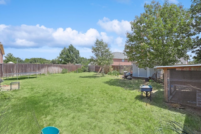 view of yard with a fenced backyard, a trampoline, and an outdoor structure