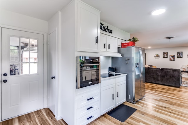 kitchen with white cabinets, stainless steel appliances, decorative backsplash, and light hardwood / wood-style flooring