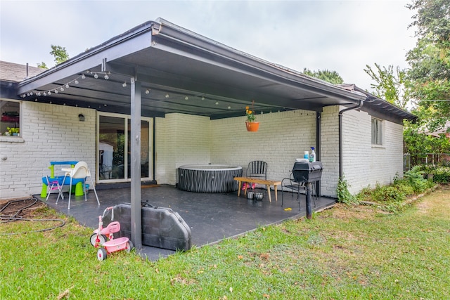 back of house with a patio area, a yard, and a hot tub