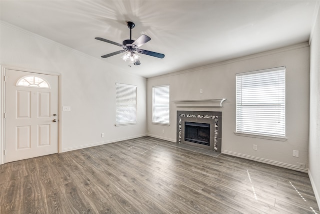 unfurnished living room featuring a wealth of natural light, a tiled fireplace, ceiling fan, and hardwood / wood-style flooring